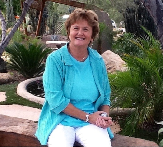 A woman sitting on the ground in front of some trees.